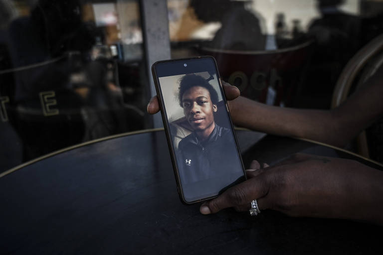 Ann Marie Lawrence holds a phone showing her son Giovanni Lawrence, who was convicted of murder in a so-called joint enterprise case, in Manchester, England on July 14, 2022. The zealous use of joint-enterprise case prosecutions is one example of how British political leaders have pursued criminal justice policies that disproportionately punish Black people. (Mary Turner/The New York Times)