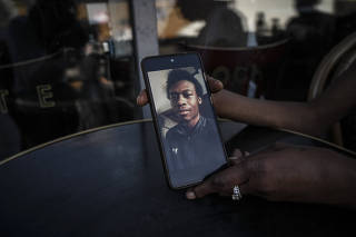 Ann Marie Lawrence holds a phone showing her son Giovanni Lawrence, who was convicted of murder in a so-called joint enterprise case, in Manchester, England on July 14, 2022. (Mary Turner/The New York Times)