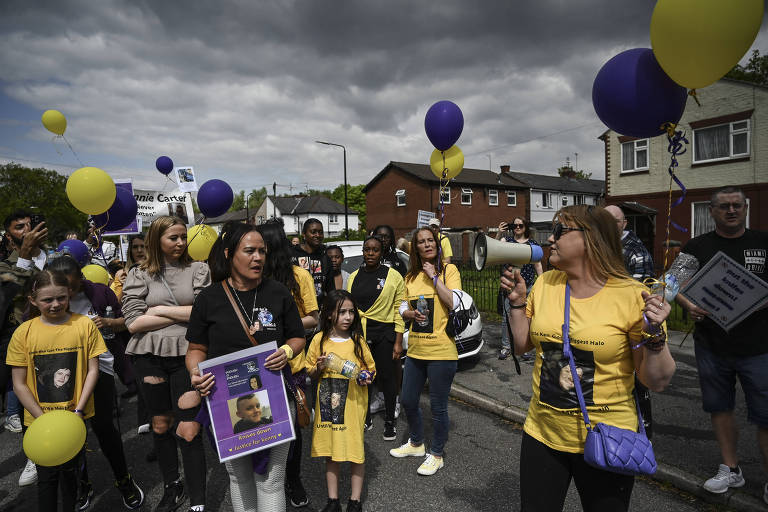 Kelly Brown, center, holding a poster, whose son Rhamero West was fatally stabbed, in May during an anti-knife-crime march in Manchester, England on May 7, 2022. The zealous use of joint-enterprise case prosecutions is one example of how British political leaders have pursued criminal justice policies that disproportionately punish Black people. (Mary Turner/The New York Times)