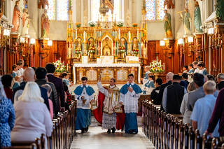 Rev. Canon Jean-Baptiste, center, sprinkles holy water on parishioners at St. Joseph Shrine during a Latin Mass, which it now celebrates three times on Sunday mornings and twice on most weekdays, in Detroit, Oct. 2, 2022. (Nick Hagen/The New York Times)