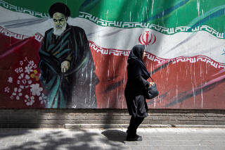 FILE PHOTO: An Iranian woman walks in front of a mural of Iran's late leader Ayatollah Ruhollah Khomeini in Tehran