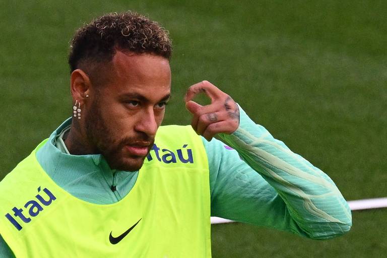 Usando colete amarelo e camiseta verde, Neymar leva a mão esquerda ao rosto durante treinamento da seleção brasileira em Turim, na Itália