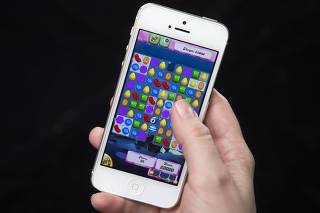 File photo of a woman posing for a photo illustration with an iPhone as she plays Candy Crush in New York