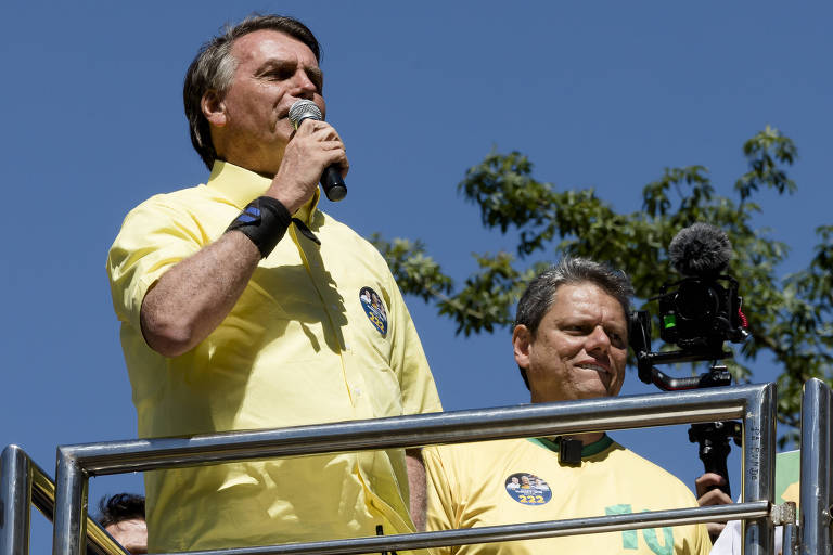 Bolsonaro fala ao microfone em dia de bastante sol; os dois candidatos vestem camisas amarelas