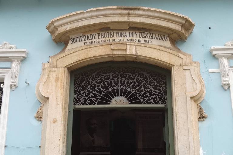 Fachada de casarão de cor azul. Acima da porta, o nome da entidade está gravado em pedra