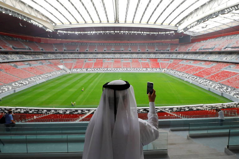 Pessoa tira com celular foto do gramado e das arquibancadas do estádio Al Bayt, na cidade de Al Khor, que abrigará a cerimônia de abertura e também o primeiro jogo da Copa do Mundo do Qatar