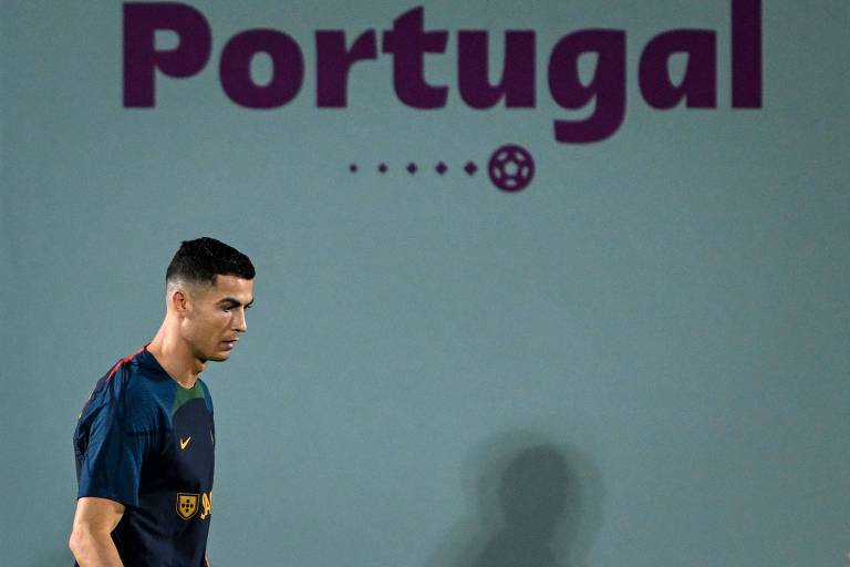 Cristiano Ronaldo caminha no Shahaniya Sports Club, em Al Shahaniya, onde a seleção portuguesa treina para a Copa do Mundo do Qatar; na parede atrás dele está escrito a palavra "Portugal"
