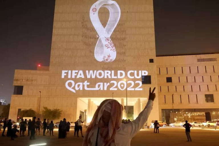 Imagem colorida, registrada à noite, mostra um prédio branco com uma logomarca iluminada. Nela está escrito Fifa World Cup Qatar 2022.
