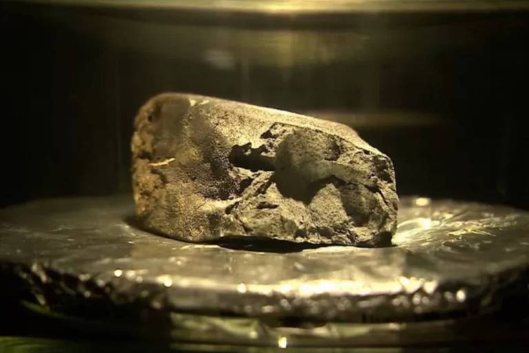 Pedaço de meteorito brilhante sob foco de luz
