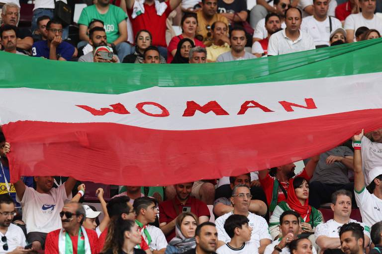 Torcedores do Irã com bandeira a favor dos direitos das mulheres, nesta segunda (21), na partida contra a Inglaterra
