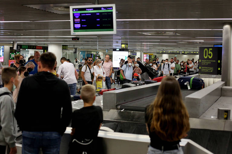Passageiros aguardam bagagens no aeroporto de Lisboa, em Portugal