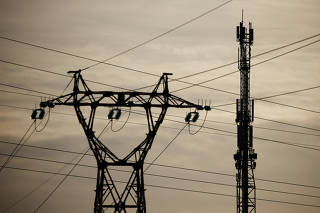 A mobile-phone relay mast is seen behind an electrical pylon in Reze
