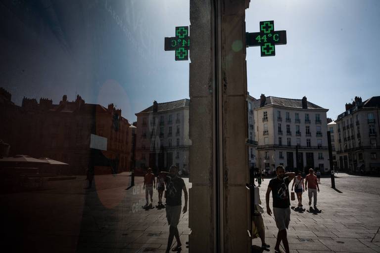 Pedestres caminham em rua de Nantes, na França, enquanto termômetro marca 44ºC
