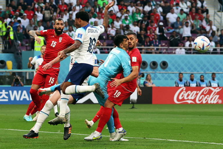 Com uniforme azul, o goleiro Beiranvand, do Irã, colide de cabeça com o colega de seleção Hosseini no jogo contra a Inglaterra, na Copa do Qatar