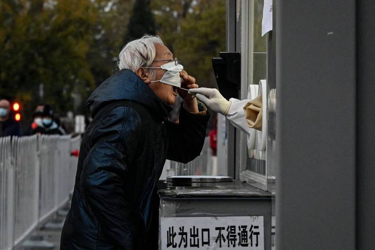 Profissional colhe amostra de teste para coronavírus de idosa, em estação de cabines de exame em Pequim, capital da China 