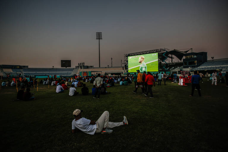 Migrantes assistem a partida da Copa em Faz Zone de Asian Town, na perifeira de Doha
