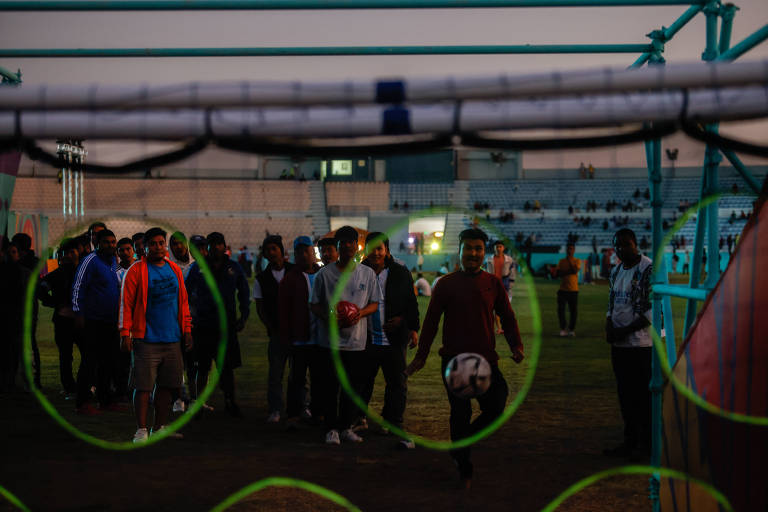 Migrantes participam de competição de chute a gol na Fan Zone de Asian Town, na periferia de Doha
