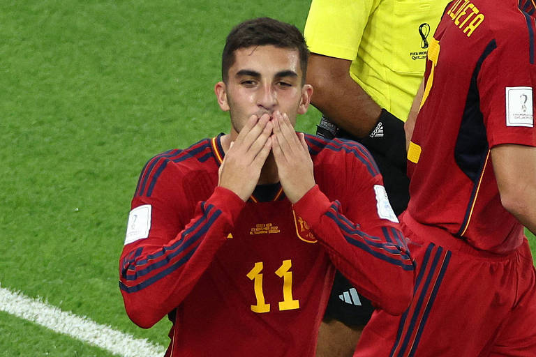 O jogador da Espanha Ferran Torres, de uniforme vermelho com o número 11 em amarelo na parte da frente da camisa, está com as duas mãos na boca, em gesto de mandar beijo, depois de fazer um gol no jogo contra a Costa Rica na Copa do Mundo do Qatar