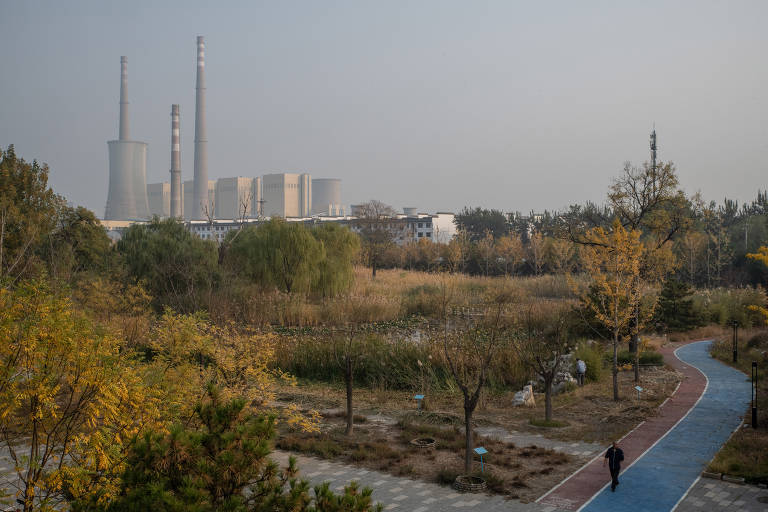 Usina de energia movida a carvão em Pequim. A fábrica está em volta de uma área arborizada e tem prédios de tamanhos diversos.