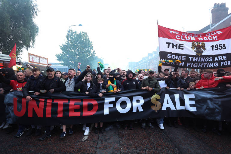 Torcedores atrás de faixa em inglês que diz "United à venda"