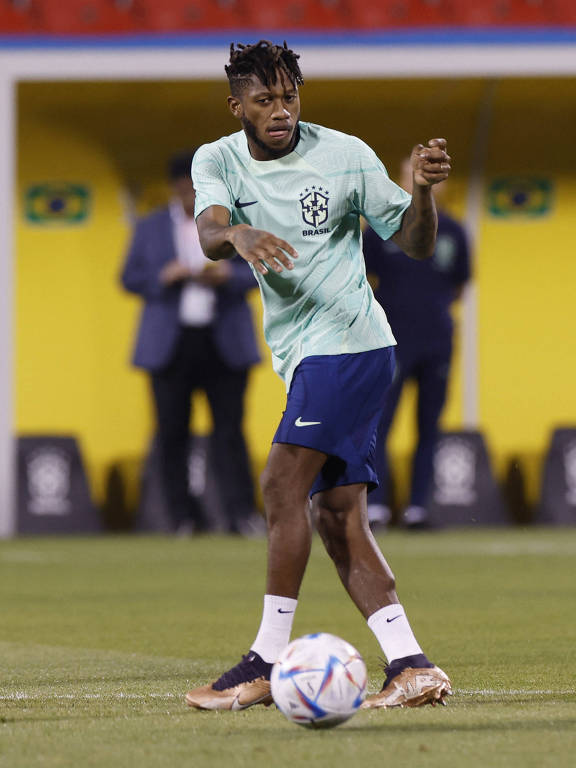 Com a bola diante de si, o volante Fred, da seleção brasileira, gira o corpo para a esquerda em treino em Doha, no Qatar 