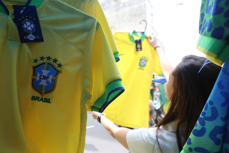 mulher perto da camiseta amarela da seleção brasileira de futebol