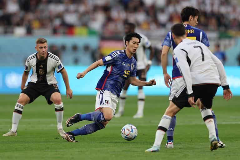 Imagem mostra jogadores da Alemanha disputando bola com japonês em um estádio.