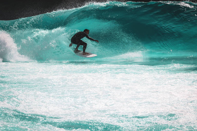 surfista agachado em cima da sua prancha de surfe preparando a posição para entrar no tubo da onda