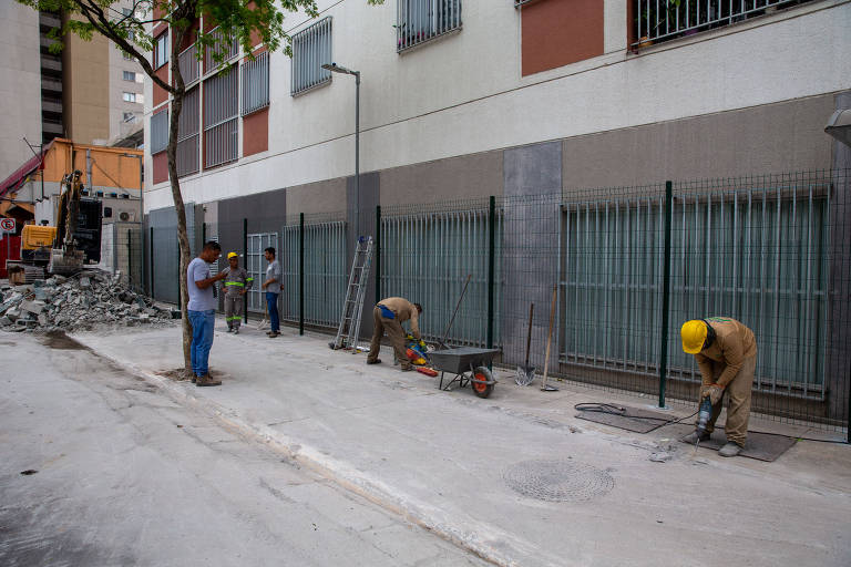Funcionários trabalham na demolição de muro e na instalação de grades de proteção