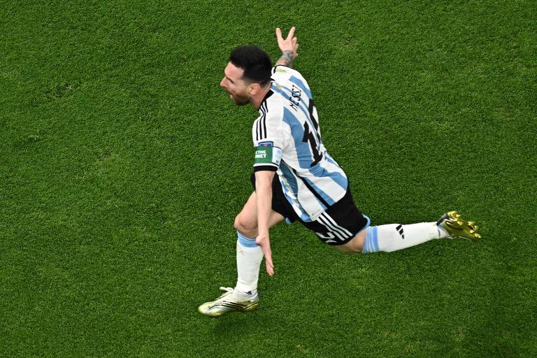 Imagem colorida mostra Messi de corpo inteiro, correndo com os braços abertos, em direção à esquerda. messi veste a camisa argentina, branca com listras verticais na cor azul claro.