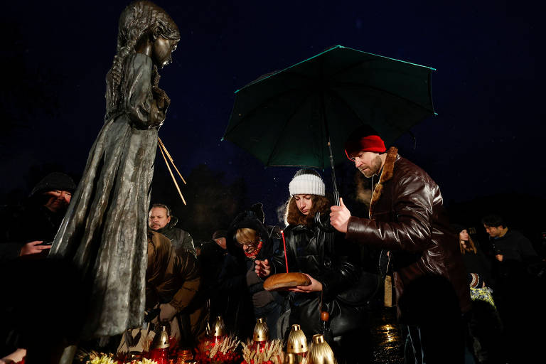 Mulher coloca um pão em um monumento às vítimas do Holodomor durante uma cerimônia de lembrança da fome de 1932-33, em Kiev