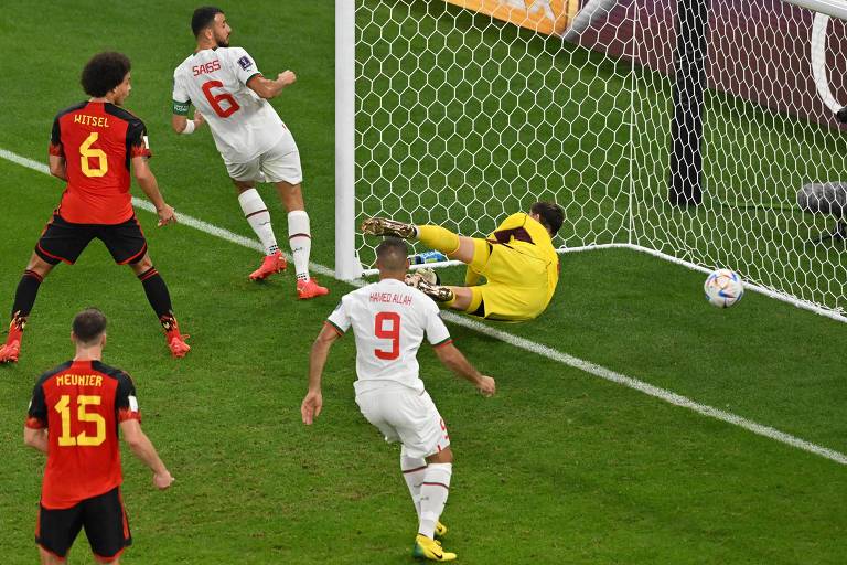 O goleiro belga, Courtois, cai dentro do próprio gol ao tentar, e não conseguir defender chute de Sabiri, desviado em Saiss, no estádio Al Thumana, em Doha