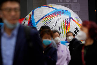 People wearing face masks walk by the giant model of FIFA World Cup Qatar 2022 match ball, amid the coronavirus disease (COVID-19) outbreak in Shanghai