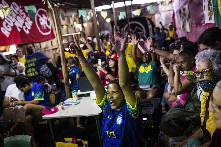 Torcedores que acompanharam o jogo na ocupação Nova Canudos, em Taipas, zona norte de São Paulo, comemoram a vitória do Brasil após o fim da partida