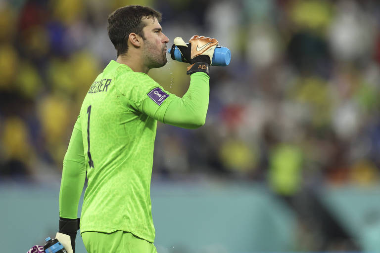 Vestido com uniforme verde com o número 1 às costas, o goleiro Alisson bebe água de uma garrafa durante a partida em Doha na qual o Brasil derrotou a Suíça por 1 a 0 na Copa do Qatar 