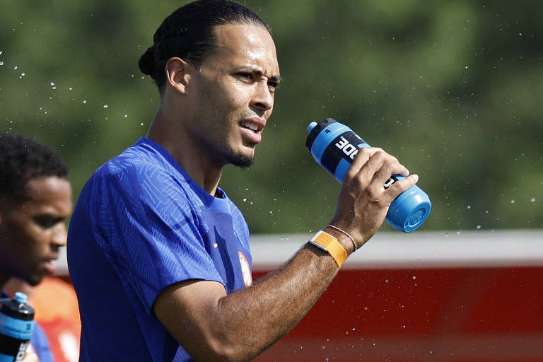 Zagueiro Virgil van Dijk bebe água em uma garrafa durante treino da Holanda
