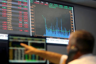 FILE PHOTO: FILE PHOTO: A man points to electronic board showing fluctuations of market indices at the floor of Brazil's BM&F Bovespa Stock Market in Sao Paulo