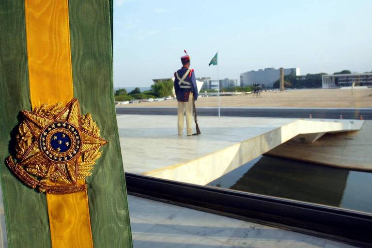 Foto mostra faixa presidencial de perto, à esquerda, com um dragão da Independência, vestido com as roupas militares ao fundo, e a Esplanada dos Ministérios