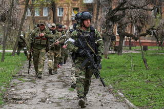 Fighters of the Chechen special forces unit walk in a courtyard in Mariupol
