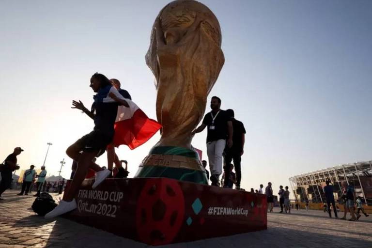 Pessoas sobem em estátua gigante da Copa do Mundo