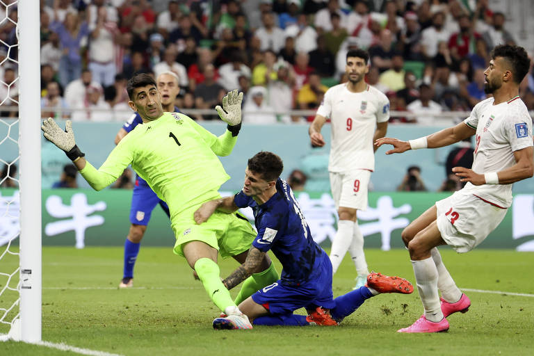 Christian Pulisic (de azul) se choca com o goleiro iraniano Alireza Beiranvand no lance em que marcou o gol da vitória dos EUA e se machucou