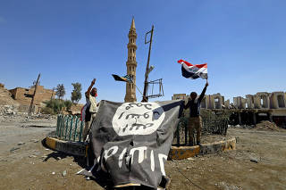 Shi'ite Popular Mobilization Forces (PMF) members hold an Islamic State flag, which they pulled down, during the war between Iraqi army and Shi'ite Popular Mobilization Forces (PMF) against the Islamic State militants in Tal Afar