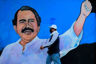 FILE PHOTO: A man, wearing a face mask for protection against the coronavirus disease (COVID-19), walks by a mural depicting Nicaraguan President Daniel Ortega, in Managua, Nicaragua March 30, 2020.