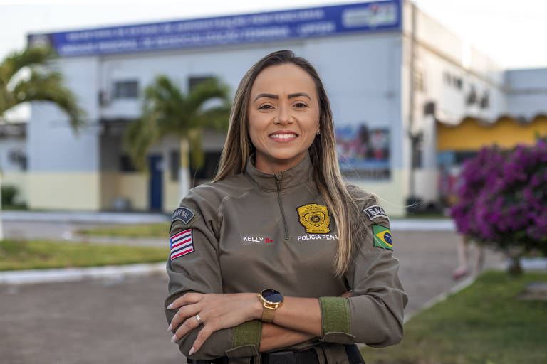 Mulher sorridente, vestida com roupa militar, cruza os braços