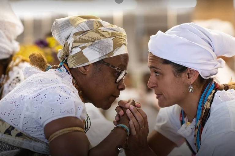 Duas integrantes do Ilê Omolu Oxum dão as mãos durante cerimônia no terreiro em São João de Meriti