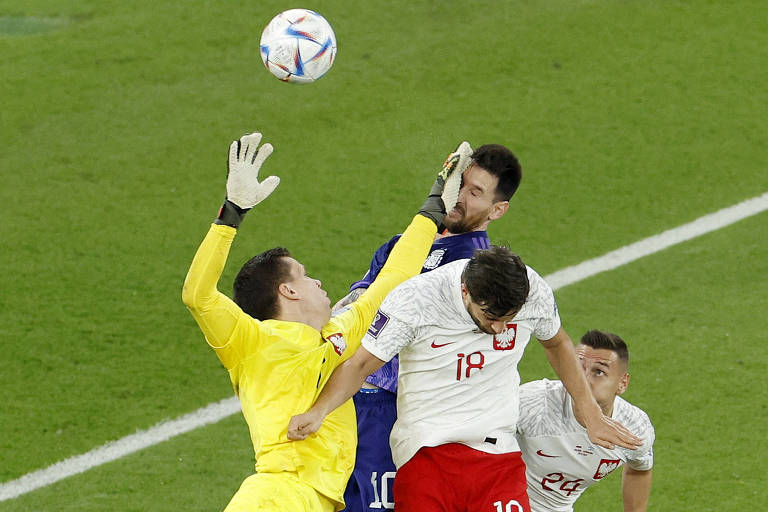 O goleiro Szczesny, de uniforme amarelo, acerta o rosto de Messi com a mão esquerda ao sair do gol para interceptar cruzamento em Polônia x Argentina no estádio 974, em Doha, na Copa do Mundo