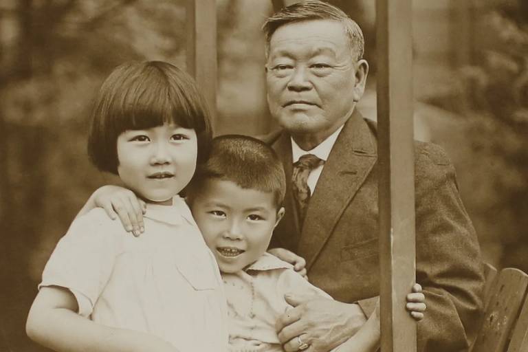 Foto em sépia de um senhor asiático com duas crianças