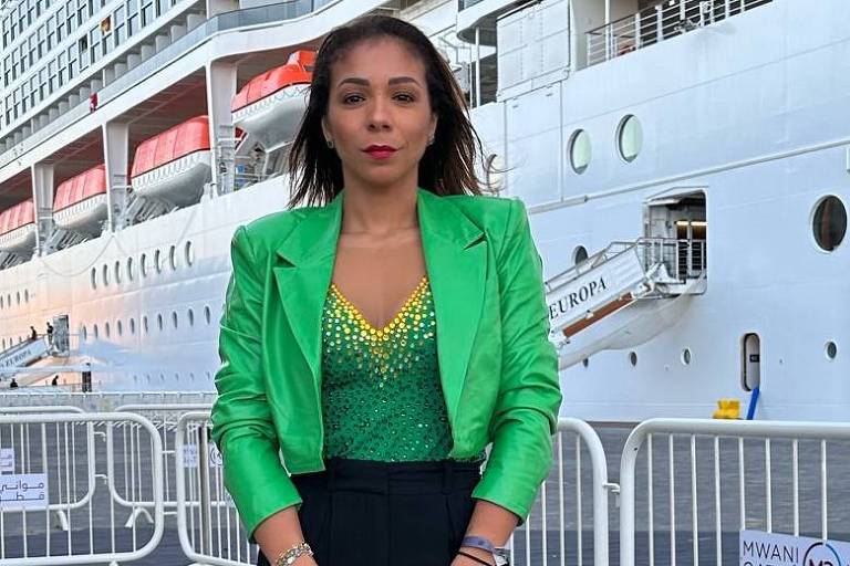 Em foto colorida, mulher posa em frente ao navio