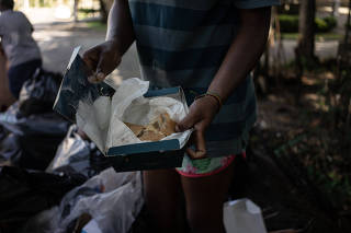 Moradora de rua pega comida no lixo