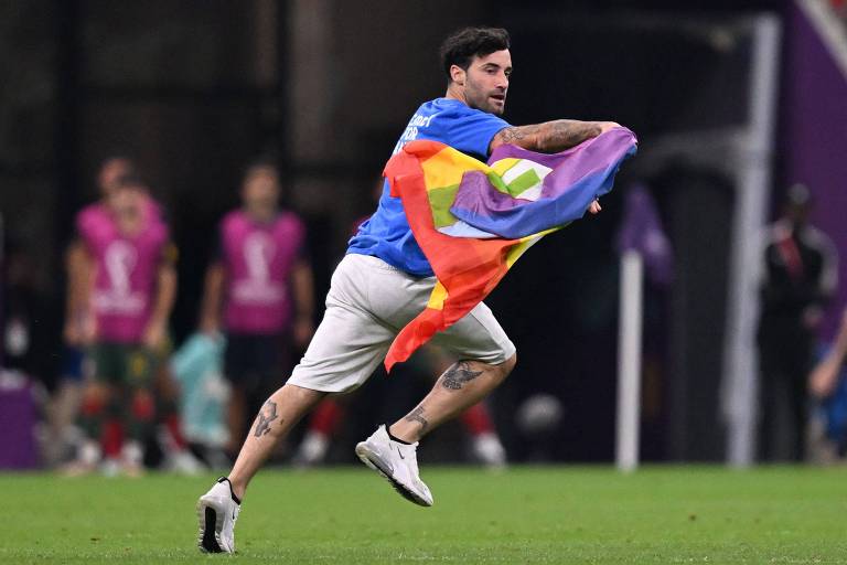 Mario Ferri, conhecido como Falcão, com a bandeira de arco-íris no gramado do estádio Lusail, durante o jogo Portugal x Uruguai, pela fase de grupos da Copa